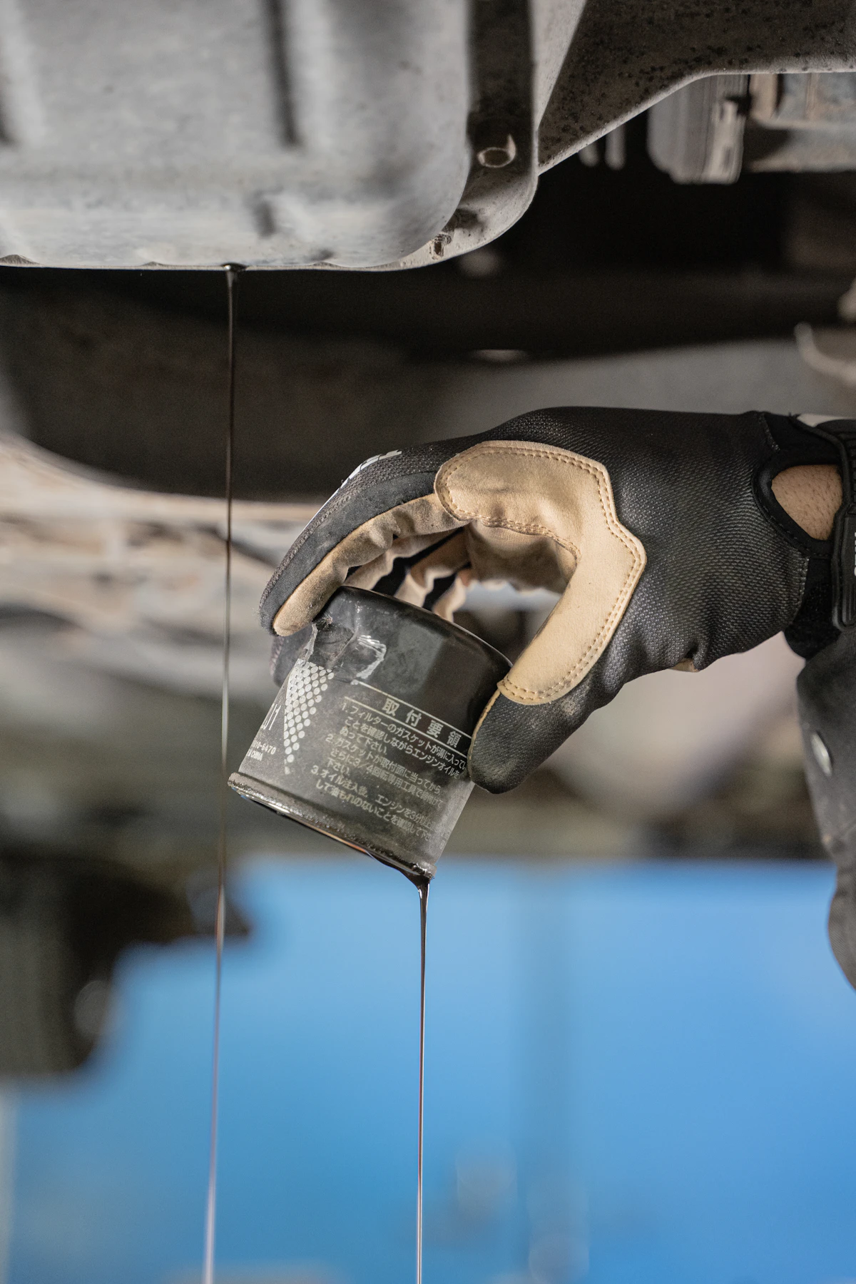 Gloved hand pouring engine oil during vehicle maintenance